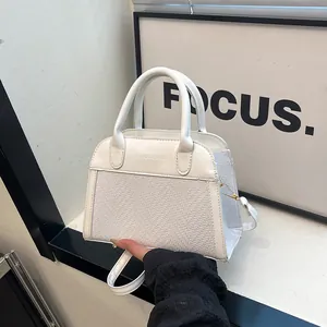 Detail of white woven textured tote bag featuring embossed logo and gold metal hardware