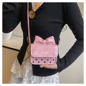 Close-up of pink mini crossbody bag with large bow and black polka dot pattern