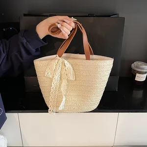 Straw tote bag with white lace bow and brown faux leather handles for beach vacations