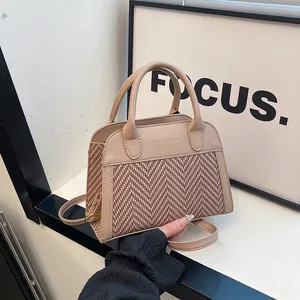 Detail of a retro herringbone patchwork handbag with dual handles and crossbody strap