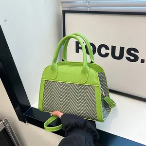 Detail of green leather handbag featuring retro herringbone fabric and fashion embossing