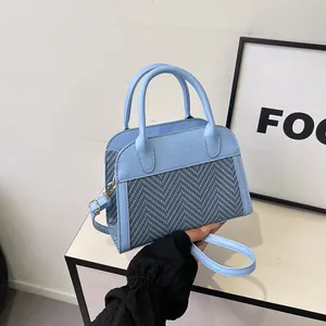 Detail of light blue tweed handbag featuring FASHION & BAGS embossed lettering and dual handles