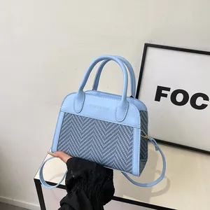 Detail of light blue woven tweed tote bag with smooth leather trim and crossbody strap