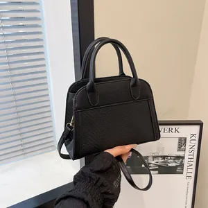 Close-up of black leather bag with FASHION & BAGS logo and golden hardware details