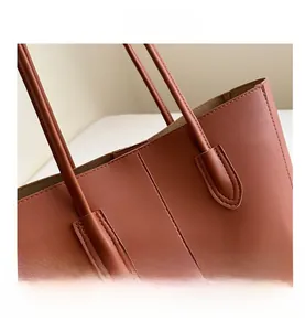 Close-up of caramel leather tote bag with fine double-stitch seams and slim handles