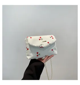 Détail du sac bandoulière en velours côtelé beige avec motifs cerise et chaîne