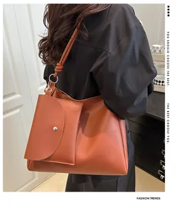 Detail of a brown leather tote bag with bucket pouch showing ring and knot strap