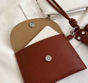 Detail of reddish-brown leather mini bucket bag charm with silver magnetic buckle