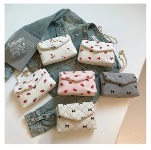 Detailed view of corduroy crossbody bags with cherry prints and gold chain straps