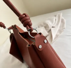 Close-up of silver ring hardware and knotted leather strap on brown bucket bag