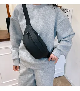 Detailed view of a black minimalist waist bag worn across the chest on a model