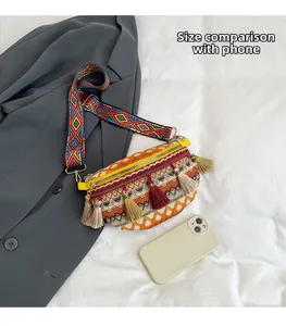 Ethnic woven chest bag with tassels and shoulder strap next to phone for size reference