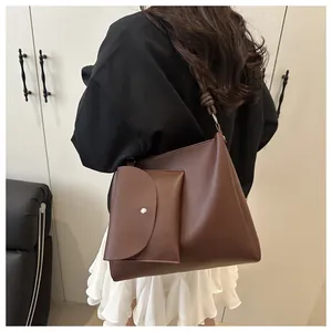 Detail of dark brown leather bucket bag featuring a knot-decorated shoulder strap and mini pouch