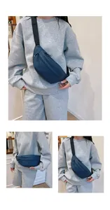 Detail view of a navy blue nylon waist bag with adjustable strap on a sporty grey outfit