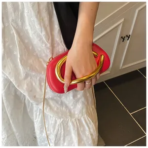 Macro detail of red evening bag with U-shaped gold metal handle and chain strap