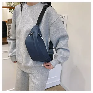 Detail of navy blue nylon chest bag featuring adjustable strap and white zipper pullers