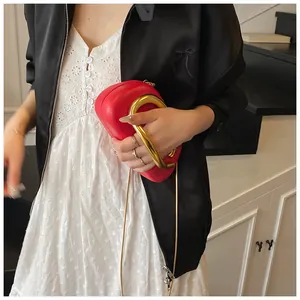 Detail of red hard-shell evening bag with bold U-shaped matte gold metal handle