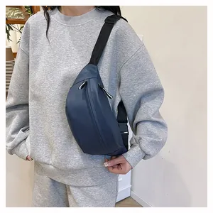 Detail view of navy blue nylon crossbody chest bag with adjustable strap worn on grey hoodie