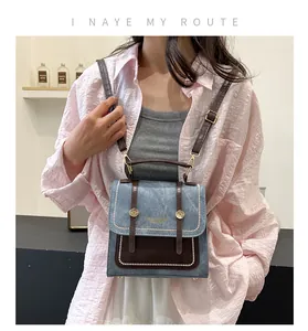 Détail du sac à dos en denim bleu et cuir marron avec clous dorés et lettrage chic