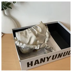 Primer plano del bolso saco de seda champán con bordado floral en caja de regalo