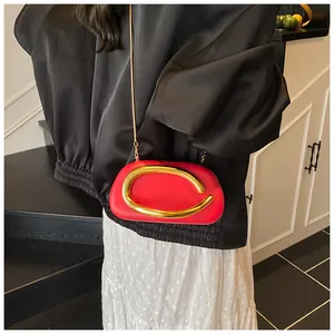 Detail of red clutch with a large gold ring buckle and elegant metal chain strap