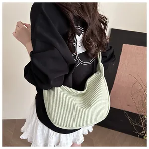 Detail of light green corduroy underarm bag featuring soft texture and knot strap design