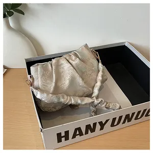 Detalle del bolso de seda champán con bordados de paisajes chinos y asa suave