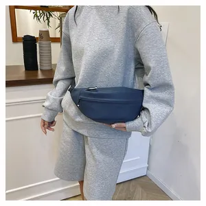 Detail view of navy blue nylon waist bag with multiple zippers worn by a female model