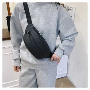 Close-up of black nylon crossbody fanny pack with white drawstring zippers for daily sport