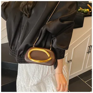 Detail of vintage brown crossbody bag with C-shaped gold metal buckle and chain strap