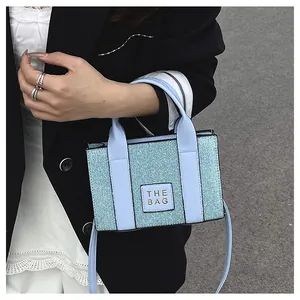 Gros plan du sac cabas à paillettes bleu clair avec l'étiquette THE BAG et les poignées
