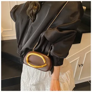 Detailed view of the dark brown clutch with gold C-shaped metal handle and chain strap