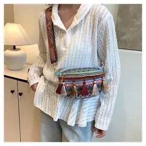 Detail of colorful woven crossbody bag featuring bohemian tassels and patterned strap