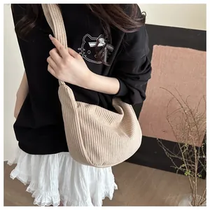 Detail of beige corduroy crossbody crescent bag with soft texture and wide shoulder strap