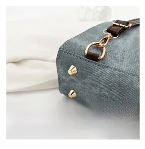 Gros plan des crochets en métal doré et anneaux en D sur le sac à main en denim bleu