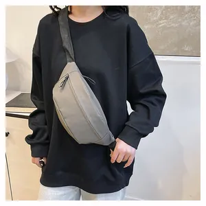 Detailed view of light gray matte nylon chest bag with black wide strap on model