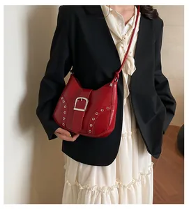 Details einer roten Leder-Schultertasche mit Silberschnalle und Ösen am Modell