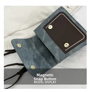 Détail des boutons magnétiques du sac et du contraste entre cuir bleu texturé et marron