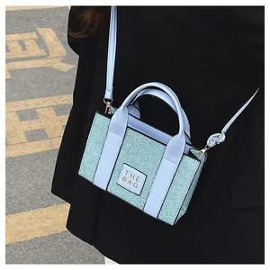 Vue détaillée du sac cabas bleu clair texturé avec poignée et bandoulière