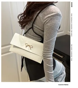 Detailansicht der weißen Umschlagtasche mit goldener Schleife und Metallkettenriemen