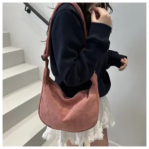 Detail view of pink corduroy crossbody bag with adjustable wide shoulder strap on model