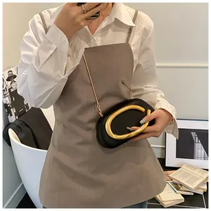 Detail of a black leather clutch bag with a large gold circular handle and chain strap