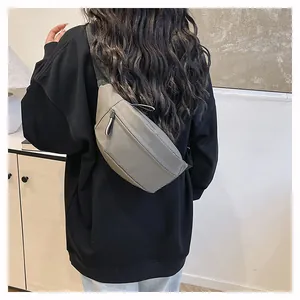 Detail view of a minimalist grey nylon waist bag with adjustable black strap on person