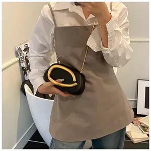 Detail of black leather clutch with oversized gold horseshoe handle and metal chain strap
