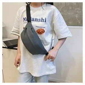 Detail showing charcoal grey waterproof nylon chest bag worn across model in casual outfit