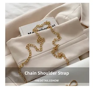 Detail of light gold chain shoulder strap with classic ring links on white fabric