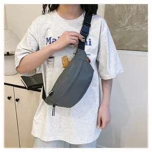 Close-up of a stylish grey nylon waist bag worn across the chest on a white t-shirt