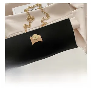 Close-up of a white leather bag featuring a gold magnetic clasp and black lining detail