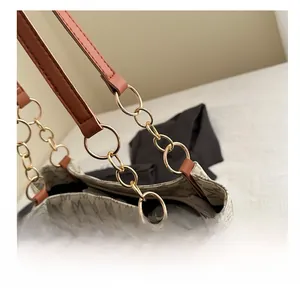 Détail de la chaîne dorée et de la bandoulière en cuir sur un sac monogramme
