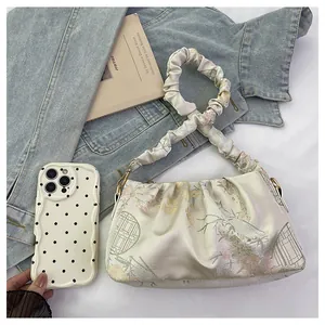 Detalle de bolso satinado con estampado floral y funda de móvil con puntos negros